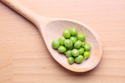 Nutritious looking peas on a wooden spoon.