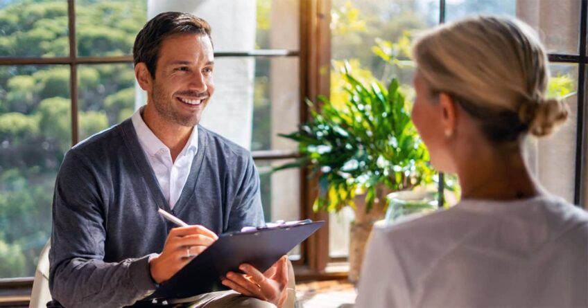 Male therapist taking notes with female client